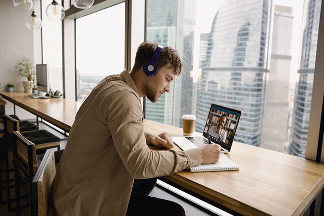 Man wearing headphones while looking at laptop.